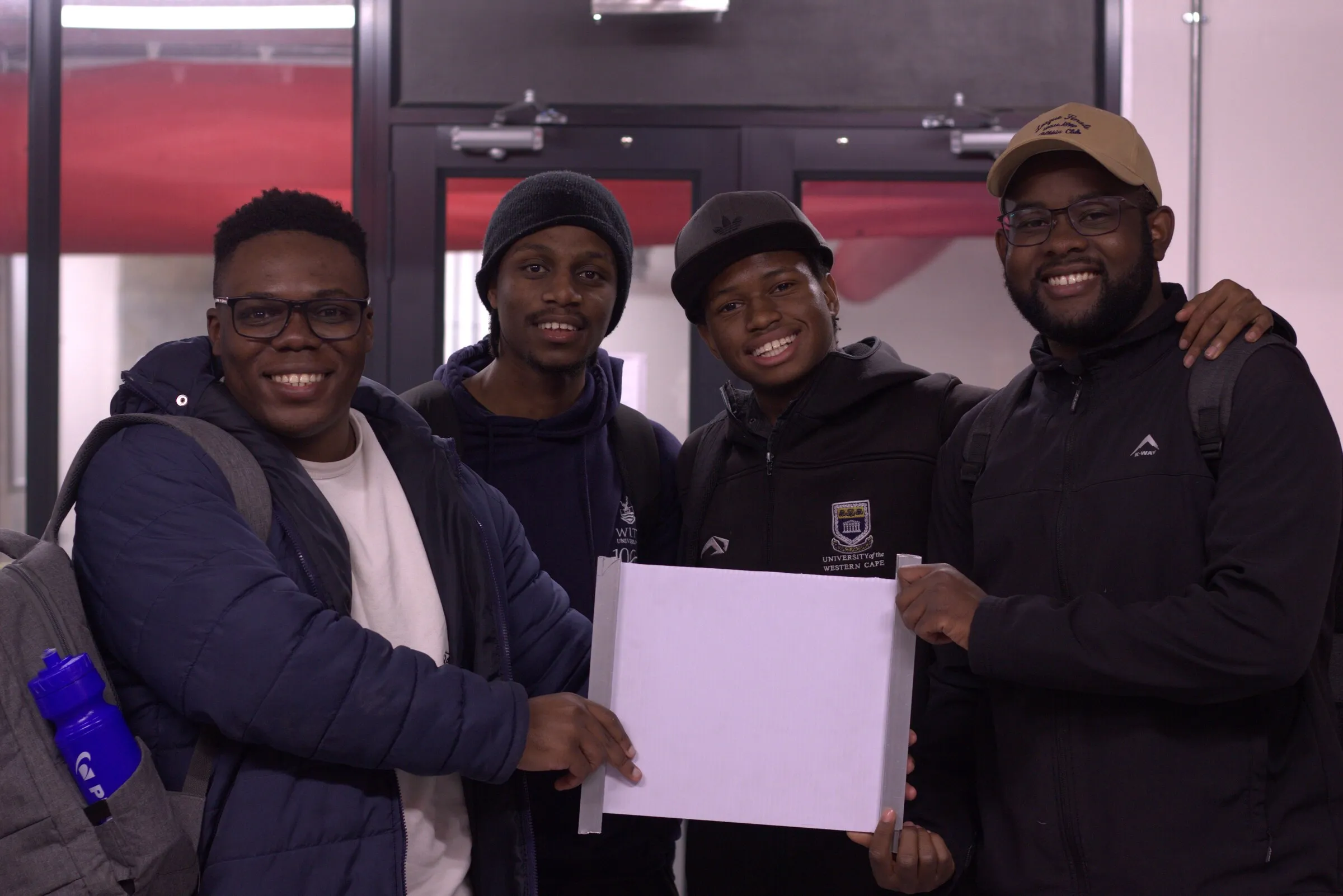 Vele with three teammates from the Engineers Without Borders challenge, holding up their entry.